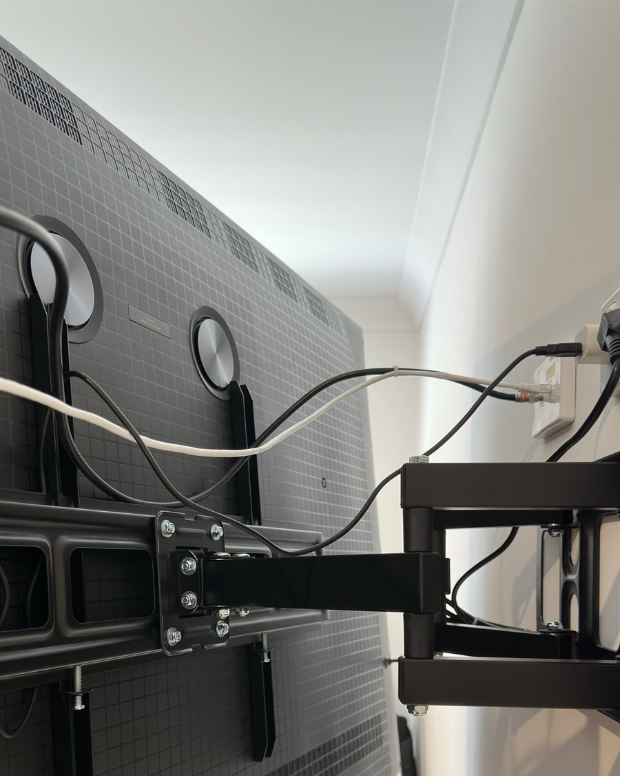 Flat-screen TV wall-mounted on a full-motion swing-arm bracket with cables tidied